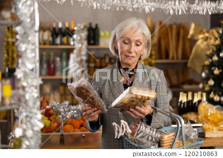 While shopping on eve of New Year holidays, elderly lady is interested in packing cookies. While shopping on eve of New Year holidays, elderly lady is interested in packing cookies. 120210863