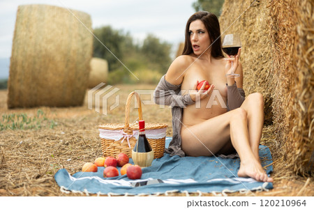 Woman sitting in robe with wine during picnic Woman sitting in robe with wine during picnic 120210964