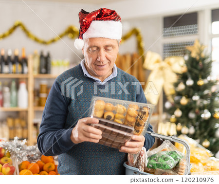 Elderly man chooses cookies and chocolates at grocery 120210976