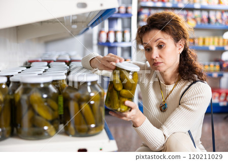 Portrait of woman buying canned cucumbers at grocery store 120211029