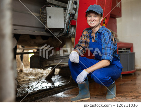 Woman pumps milk from cow, works and uses automatic milking machine. 120211030