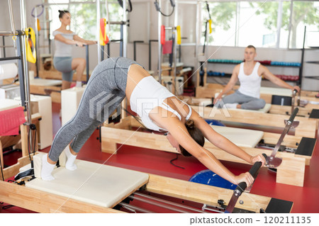 Young girl doing full body exercises lying on reformer device 120211135