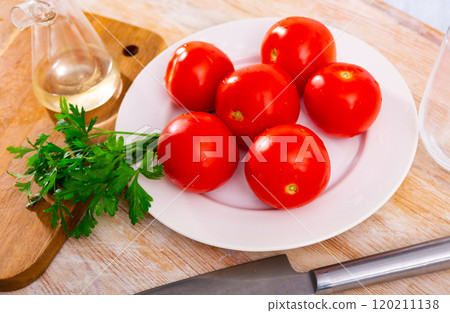 Fresh organic tomatoes on wooden kitchen table 120211138