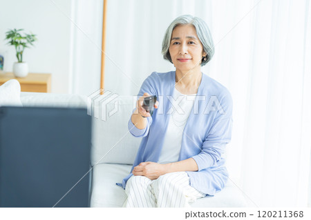 Senior woman watching TV in the living room Senior woman watching TV in the living room 120211368