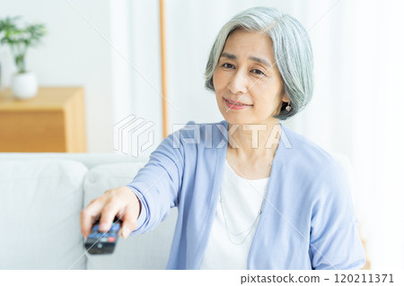Senior woman watching TV in the living room Senior woman watching TV in the living room 120211371