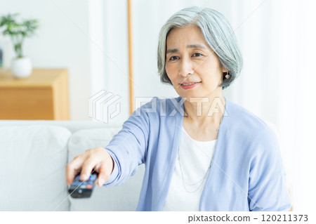 Senior woman watching TV in the living room 120211373
