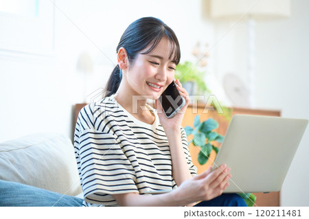 Young woman looking at computer screen, living room, one-room apartment Young woman looking at computer screen, living room, one-room apartment 120211481