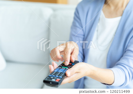 在客廳操作電視遙控器的高級女性 120211499