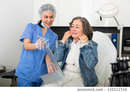 Smiling mature female patient satisfied with received cosmetological procedure in clinic 120211538