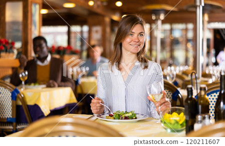 Smiling young woman having dinner in cozy restaurant Smiling young woman having dinner in cozy restaurant 120211607
