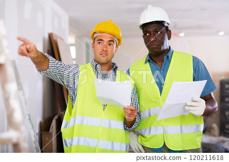 Builders having conversation about work plan in apartment 120211618
