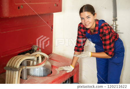 Girl monitors operation of automatic milking machine, adjusts operation of equipment Girl monitors operation of automatic milking machine, adjusts operation of equipment 120211622