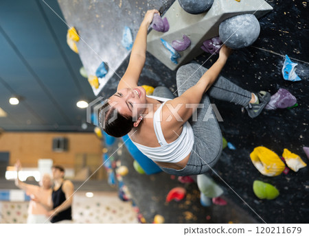 Sporty young girl doing a difficult wall climb in climbing gym Sporty young girl doing a difficult wall climb in climbing gym 120211679