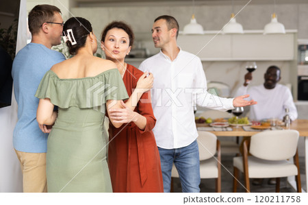 Smiling woman hostess hugging and kissing guest at dinner party Smiling woman hostess hugging and kissing guest at dinner party 120211758