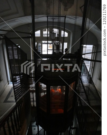 Vintage elevator in the entrance of an old house in Naples, Italy. A vintage elevator stands gracefully in the entrance of a historic Naples, Italy, house, exuding Old World charm and character. Vintage elevator in the entrance of an old house in Naples, Italy. A vintage elevator stands gracefully in the entrance of a historic Naples, Italy, house, exuding Old World charm and character. 120211769