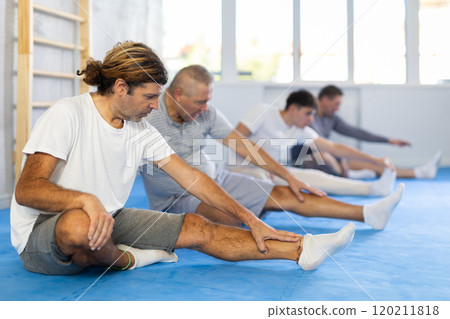 Group of men doing muscle stretching before boxing or judo class 120211818