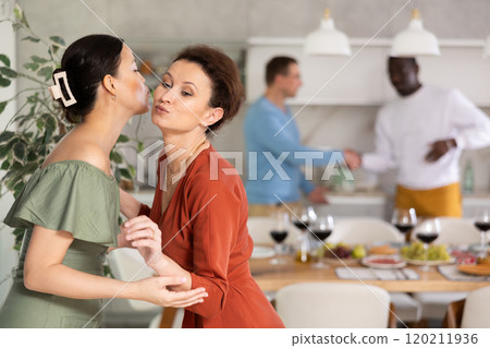 Happy middle-aged woman welcoming her guest at home 120211936