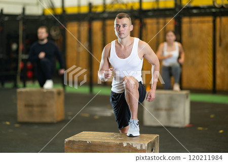 Sporty man performing box step-ups during high-intensity functional training 120211984