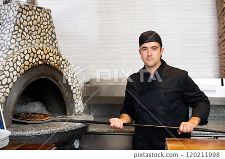 Skilled man chef preparing pizza in restaurant Skilled man chef preparing pizza in restaurant 120211998