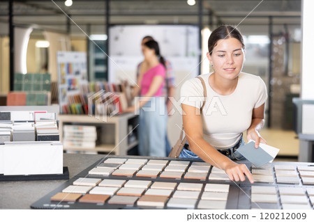 Girl exploring tile samples on display board in building hypermarket 120212009