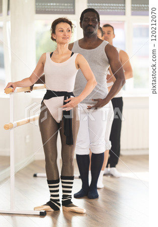 Group of dancers stand in first position at barre 120212070