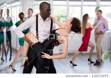 Woman dances incendiary tango with African man partner during choreography lesson Woman dances incendiary tango with African man partner during choreography lesson 120212075