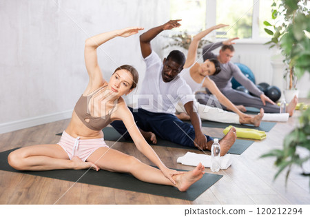 Young woman doing Parivrtta Janu Sirsasana asana in yoga studio Young woman doing Parivrtta Janu Sirsasana asana in yoga studio 120212294