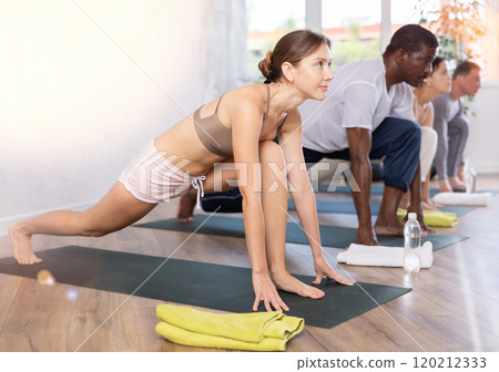 Young sporty woman doing Ashwa Sanchalanasana lunging yoga pose 120212333