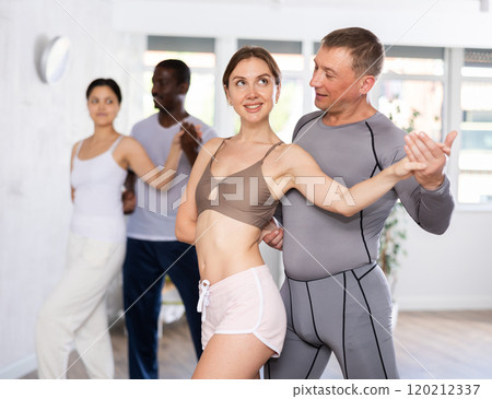 Group of multiethnic active people dancing social dance movements in studio 120212337