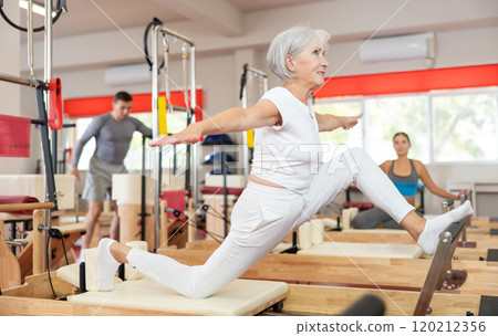 Elderly woman doing stretching on pilates machine 120212356