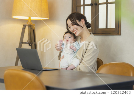 A woman in a suit holding a baby and working 120212463