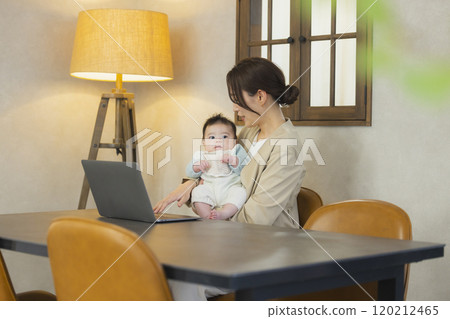 A woman in a suit holding a baby and working A woman in a suit holding a baby and working 120212465