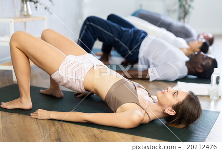 Young woman doing Setu Bandha Sarvangasana in yoga studio 120212476