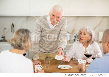 Two mature married couples playing card game poker 120212593