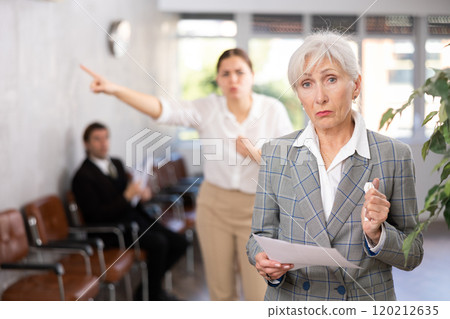 Upset elderly woman with documents in office 120212635