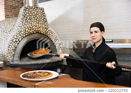 Woman pizza chef at work in restaurant Woman pizza chef at work in restaurant 120212755