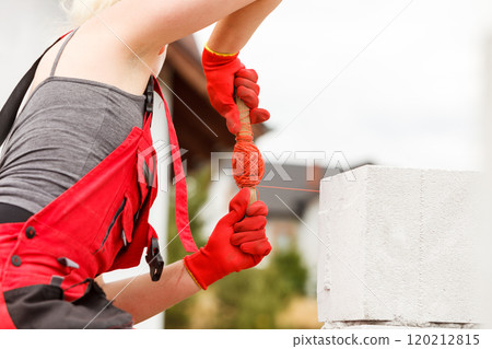 Woman leveling airbricks on construction site Woman leveling airbricks on construction site 120212815