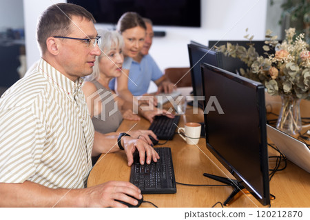 Middle-aged man learning computer programs in training room 120212870