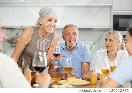 Cheerful elderly women and man gathering around kitchen table 120212875