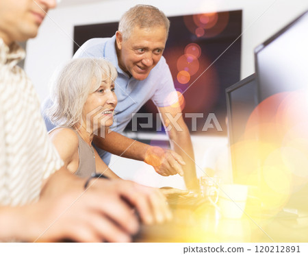 Experienced teacher of computer class assisting enthusiastic woman 120212891