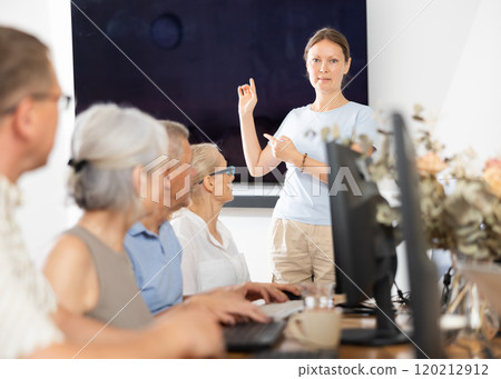 Woman teacher teaching elderly people how to use computer Woman teacher teaching elderly people how to use computer 120212912