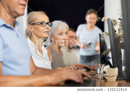 Senior woman attending computer class under guidance of teacher Senior woman attending computer class under guidance of teacher 120212914