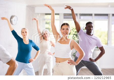 Young woman teaching group of multiethnic mature people classical dance 120212965