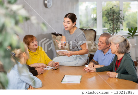 Young psychologist together with elderly adults have group therapy round table 120212983