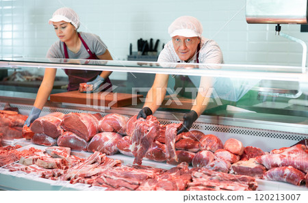 Male farmer of meat products in butcher shop offers to buy fresh beef tenderloin. 120213007