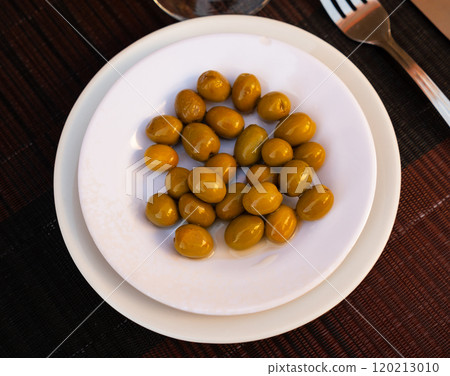 On white plate lies portion of large ripe green olives with stone. On white plate lies portion of large ripe green olives with stone. 120213010