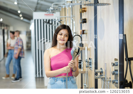 Asian woman choosing showerheads in home improvement store Asian woman choosing showerheads in home improvement store 120213035