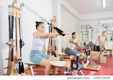 Young woman training her arms using straps Young woman training her arms using straps 120213036