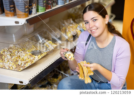 Woman holding chewing bones and scoop of dry snacks for dogs Woman holding chewing bones and scoop of dry snacks for dogs 120213059