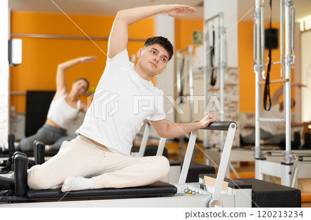 Man sits on reformer and rests while doing exercises for muscles of body and torso. 120213234